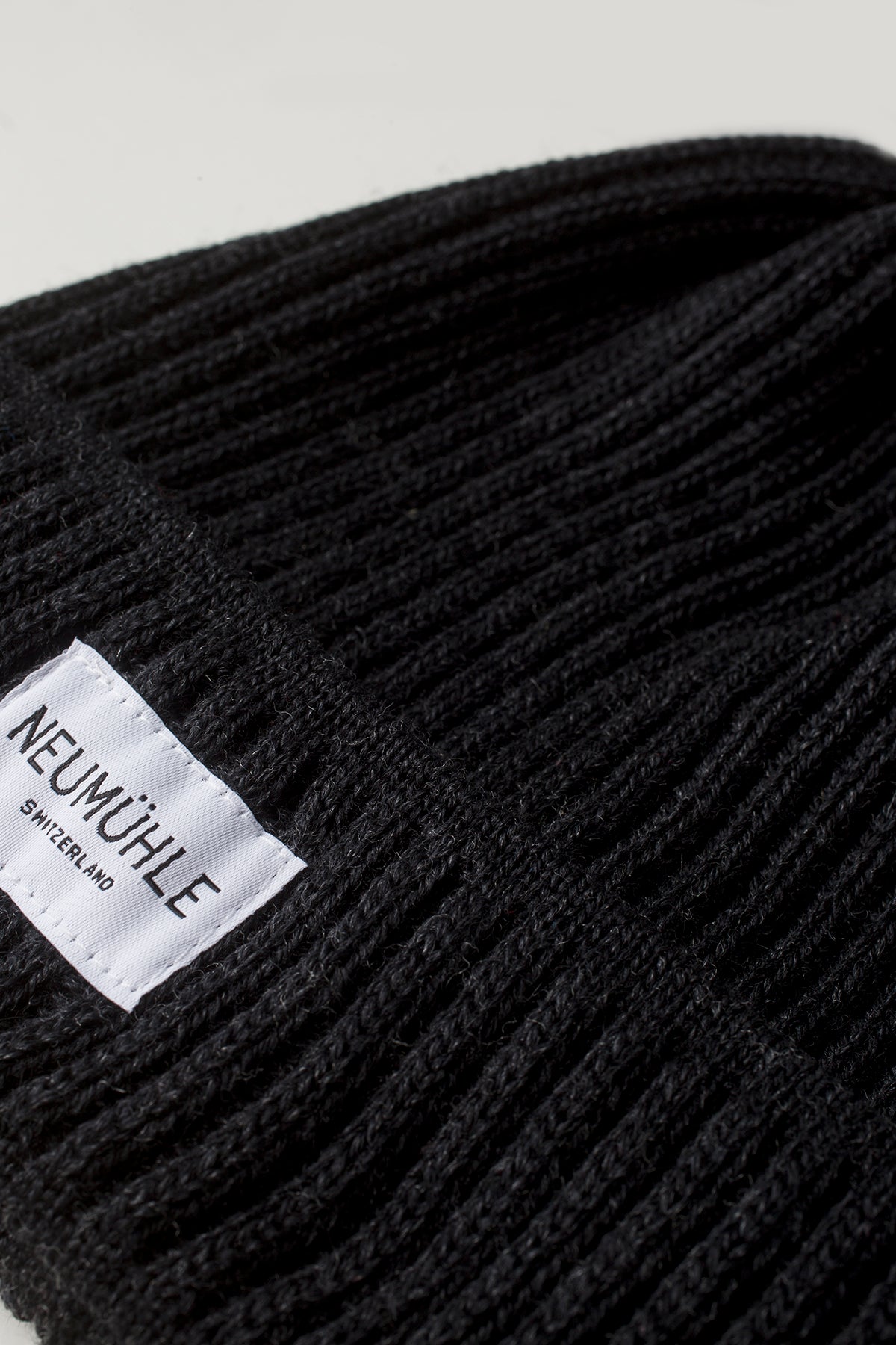 Logo detail on the sustainable beanie Elbe made of organic merino wool from Neumühle in black, locally made in Germany